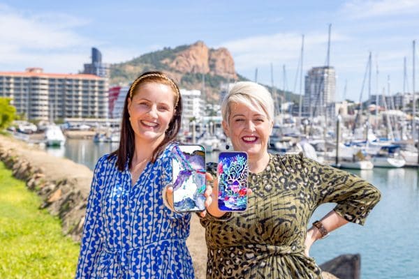 Artist Brenda Stone and NQ NFT pioneer Pamela Kerr holding smart phones with NFT art.