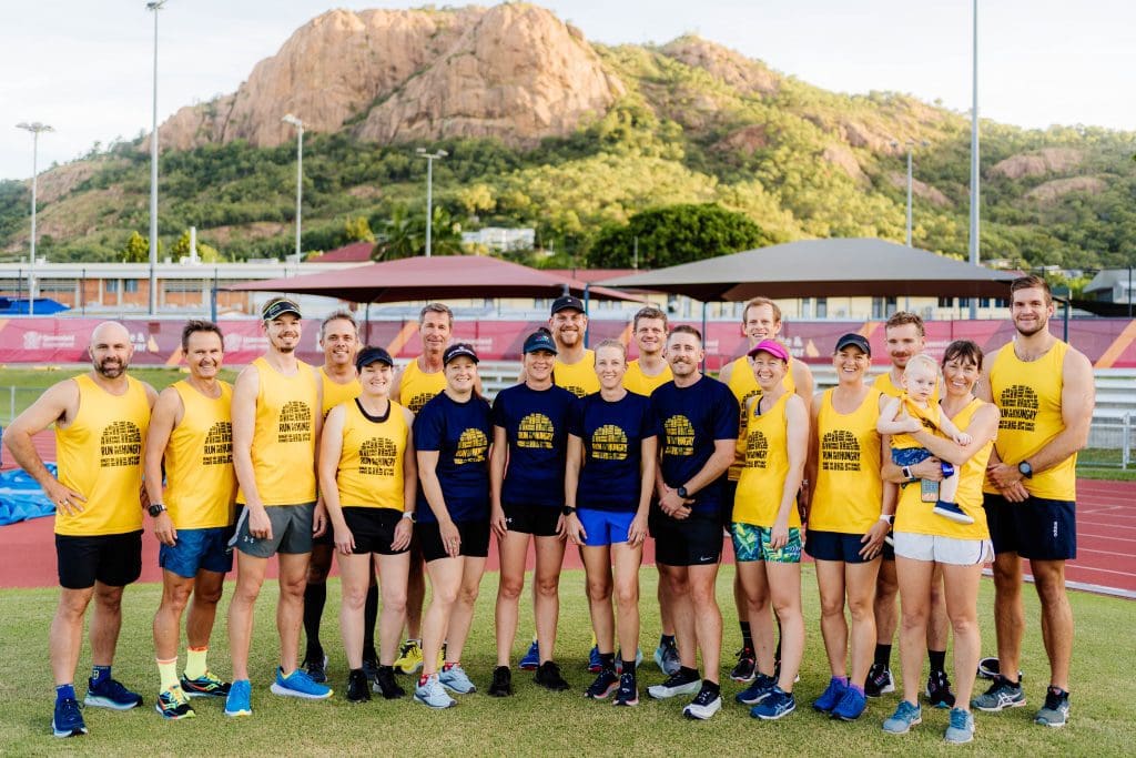 Group of coaches from Hungry Runners wearing uniform shirts and standing with Castle Hill in the background
