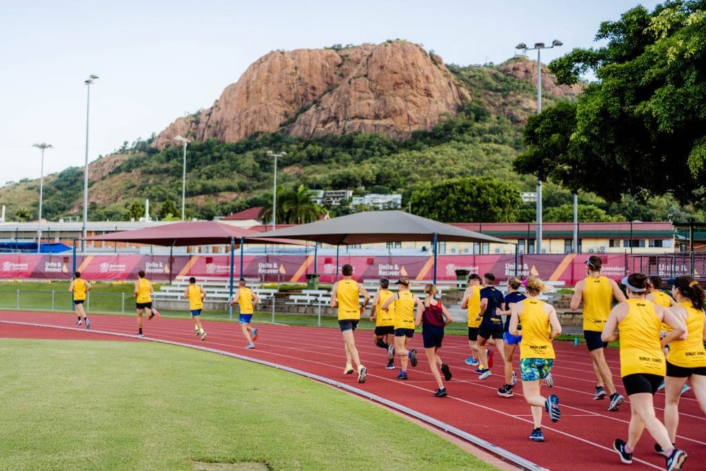 group of people running on a track wearing yellow shirts