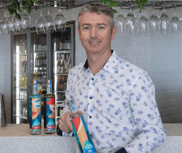 man standing at bar holding bottle of gin