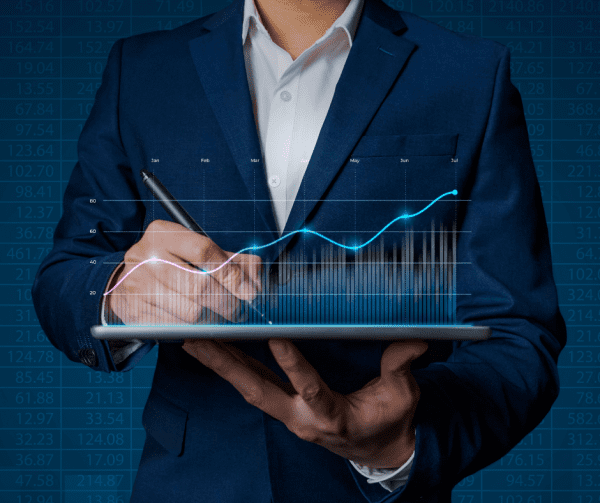 man in suit holding a tabelt and pen with a graph showing on the screen