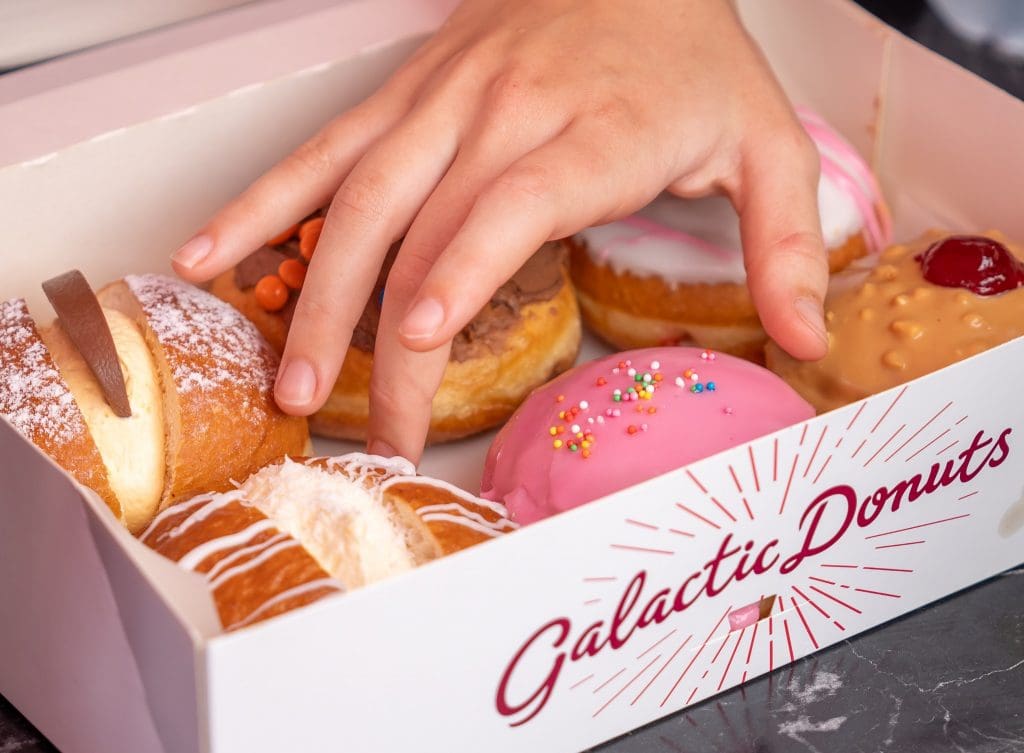 hand reaching into box of Galactic Donuts