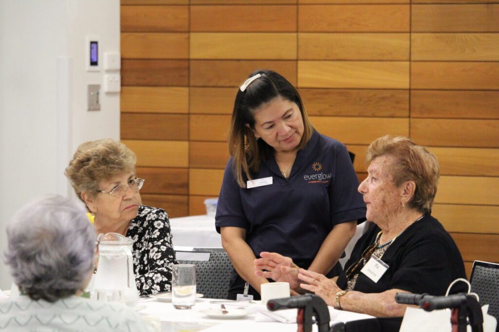 Everglow AGM 35th Anniversary November 2023 Everglow worker talking to two aged care residents at AGM meeting. BDmag