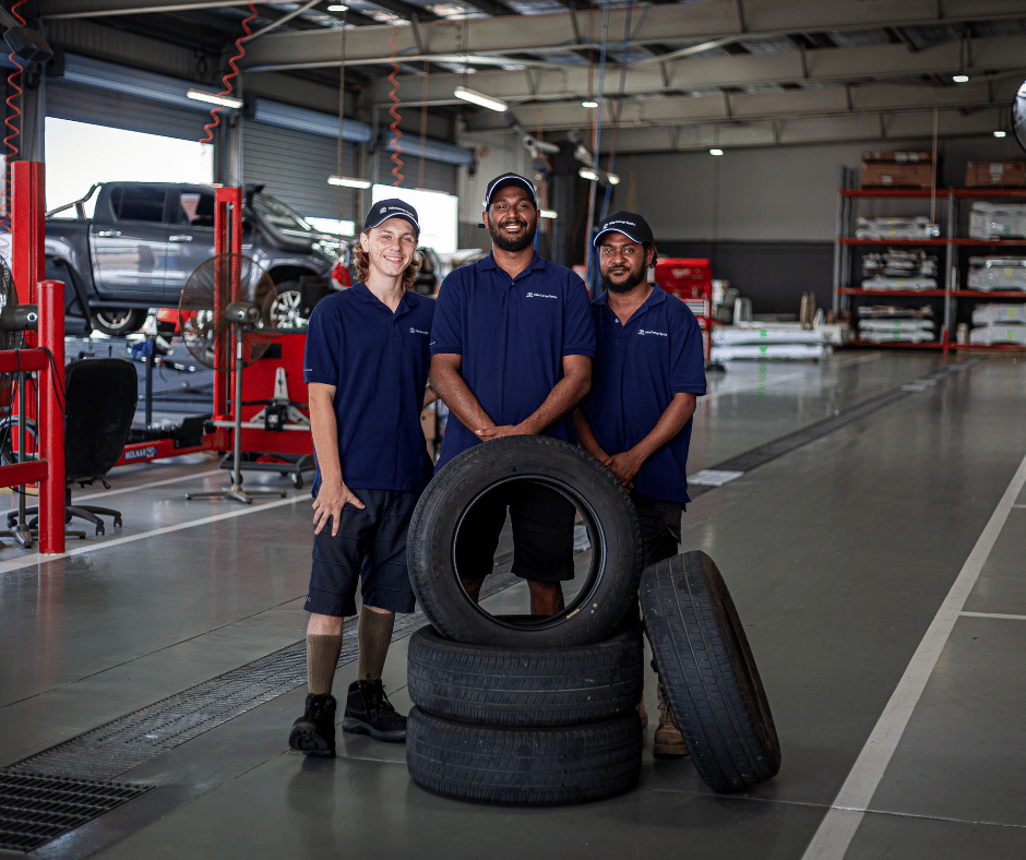 Spencer Parson, Cayless Prior and Morris Sam standing in workshop behind stack of tyres. January 2024 BDmag