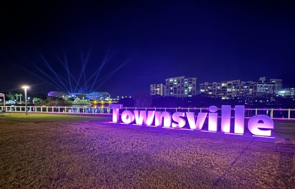 Townsville sign lit up pink with stadium in background. BDmag 2024.